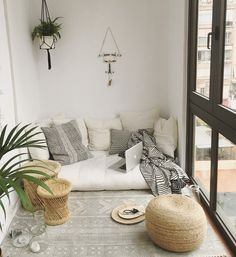 a living room filled with lots of white furniture and plants on top of the floor