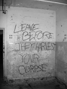 graffiti on the side of a building that says leave before they harvest your corpse