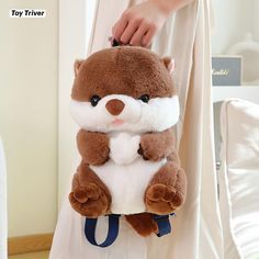 a person holding a brown and white stuffed animal on top of a blue handle bag