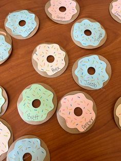 several donuts with different colored sprinkles are arranged on a wooden surface