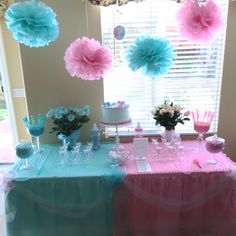 the table is decorated with pink, blue and white paper pom - poms