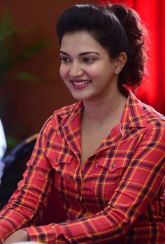 a woman sitting at a table with a laptop computer in her hand and smiling for the camera