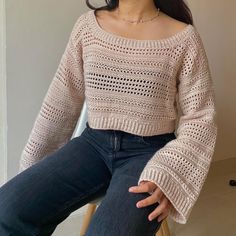 a woman is sitting on a chair and wearing a sweater with crocheted details