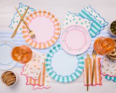 a table topped with plates and utensils next to bowls filled with food on top of a white table cloth