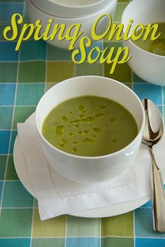 there is a bowl of soup on the table next to two bowls and spoons