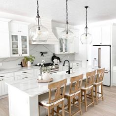 a large kitchen with white cabinets and wooden chairs in the center, along with an island