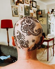 the back of a man's head with henna tattoos on it, in front of a living room