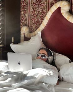 a man laying in bed with headphones on using a laptop