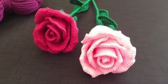 two crocheted roses sitting next to each other on top of a black surface