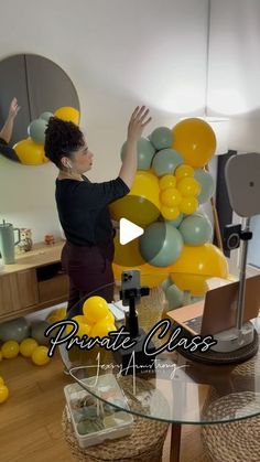 a woman standing in front of a glass table with yellow and green balloons on it