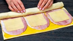 a person rolling out dough on top of a yellow mat with ham and cheese in it