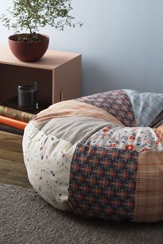 a small potted plant sitting on top of a wooden table next to a patchwork bean bag chair