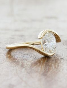 a gold ring with a white diamond on it sitting on a table next to a pair of scissors