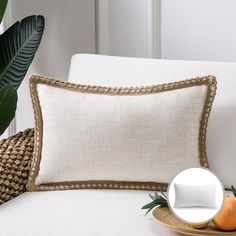 a close up of a pillow on a couch near a plate with an orange and palm leaf