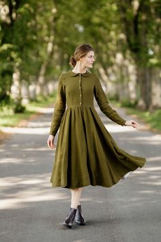 a woman in a green dress is walking down the street with her hand on her hip