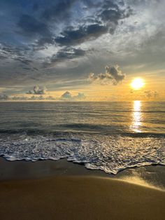 the sun is setting over the ocean with clouds in the sky and waves on the beach