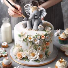 a woman is decorating a cake with an elephant figurine and flowers on it