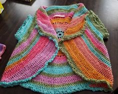 a colorful crocheted sweater sitting on top of a wooden table