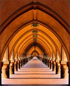 an arched hallway with columns and lights on the ceiling is shown in this image, there are