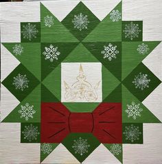 a green and red quilt with snowflakes on the bottom, an ornament in the middle