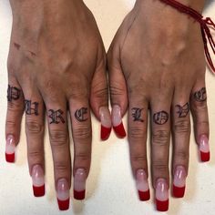 two hands with red and white nail polishes on them, one has the word love tattooed on it