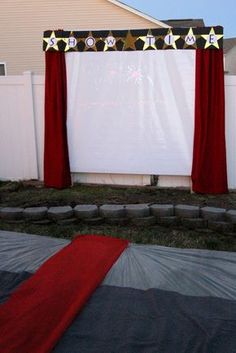 an outdoor movie screen with red curtains and stars on it