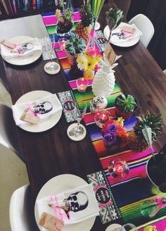 the table is set with pineapples and colorful napkins