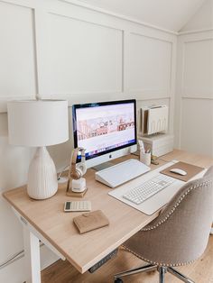 a desk with a computer, lamp and phone on it