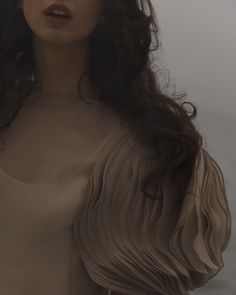 a woman with long dark hair wearing a tan dress