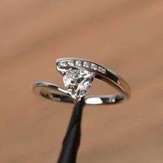 a white gold ring with a pear shaped diamond on it's side and diamonds in the middle