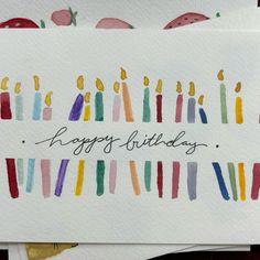 birthday card with colorful candles and the words happy birthday written in cursive writing