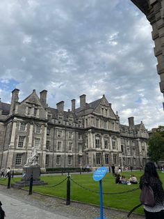 people are sitting on the grass in front of an old building