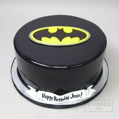 a batman birthday cake is decorated with black icing and yellow bat symbol on top