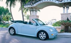 a light blue convertible car parked in front of a building with the name marina drive written on it