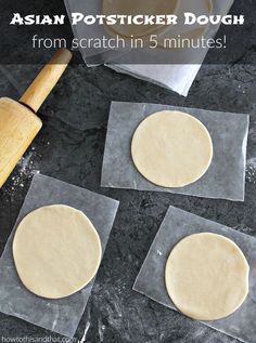 three uncooked pizza doughs sitting on top of plastic wrappers next to a rolling pin