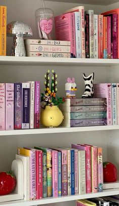 some books are sitting on top of the white bookcases in front of each other