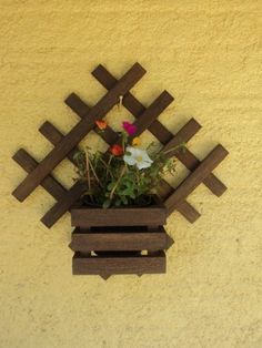 a wooden planter with flowers in it mounted to the side of a wall