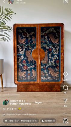 a wooden cabinet sitting on top of a hard wood floor next to a potted plant