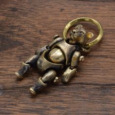 a gold colored metal key chain with a small animal on it's back, sitting on top of a wooden surface