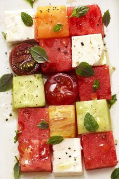 watermelon, cucumber, tomato and basil on a white platter