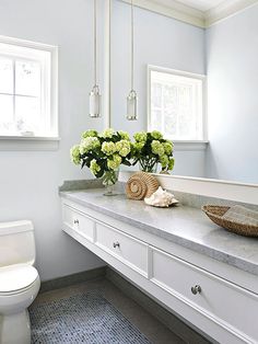 a white bathroom with flowers on the counter and a toilet in the backround