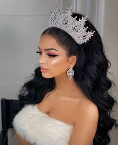 a woman wearing a tiara with long black hair and white fur around her neck