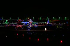 christmas lights are lit up in the night sky and reflecting on the water, along with an illuminated horse drawn carriage