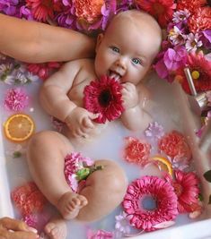 a baby sitting in a bathtub with flowers around it