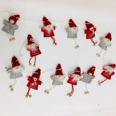 small red and silver christmas decorations on white paper with string attached to the strings, including santa's helpers