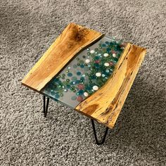 a table made out of wood and glass on top of carpeted area with grey rug