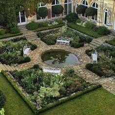 an aerial view of a formal garden with benches and water feature in the center surrounded by greenery