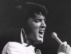 a man singing into a microphone with his mouth open and hands in front of him