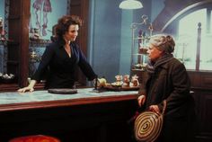 two women standing at a bar talking to each other in front of a clock on the wall