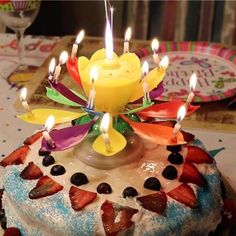 a birthday cake with candles on it and strawberries in the middle, sitting on a table